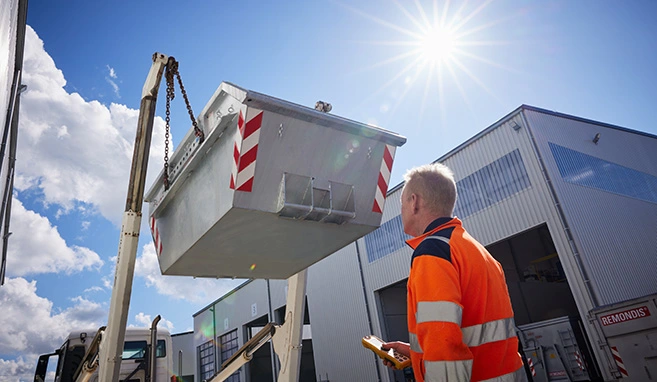 Mitarbeiter fährt Absetzkipper-Mulde mit Fernbedienung ab.