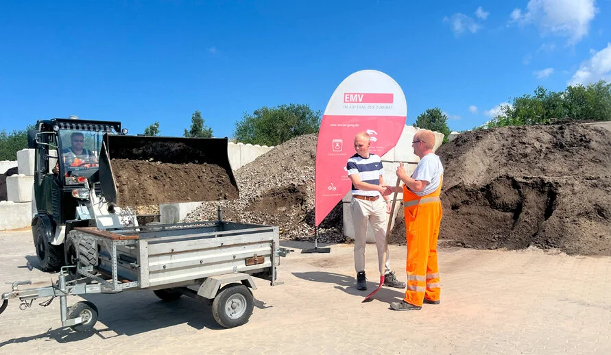Mitarbeiter lädt mineralische Baustoffe auf den Anhänger eines Kunden. 